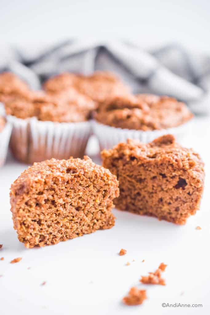 a flaxseed muffin sliced in half with more muffins behind it.