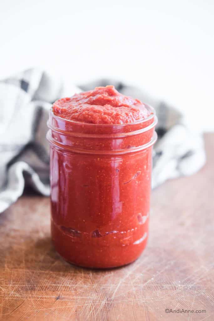 keto barbecue sauce in a mason jar with kitchen towel behind it.