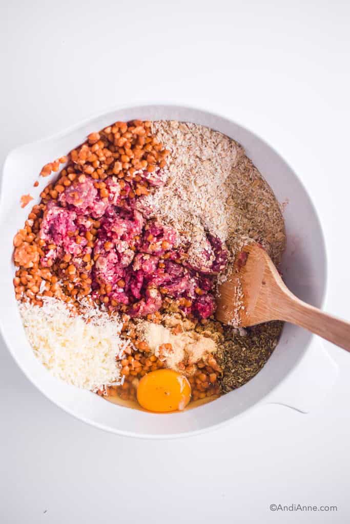 large white bowl with meatball ingredients inside: oats, lentils, ground beef, parmesan, spices and egg.