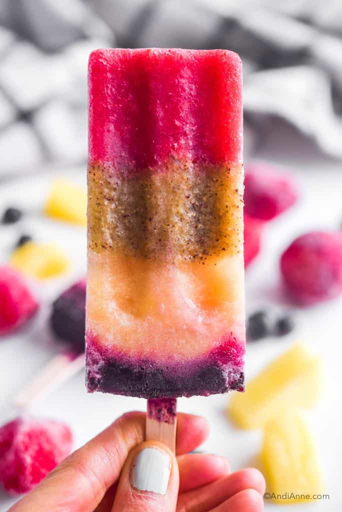 Hand holding rainbow real fruit popsicle