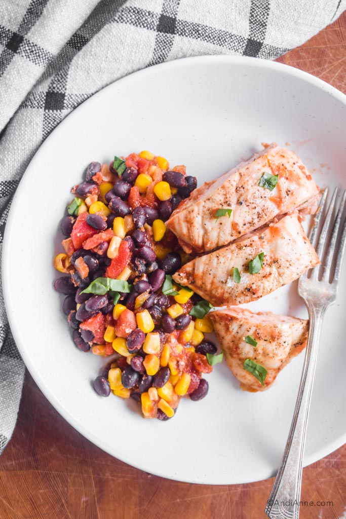 baked chicken and black bean corn salsa on a white plate with a fork.
