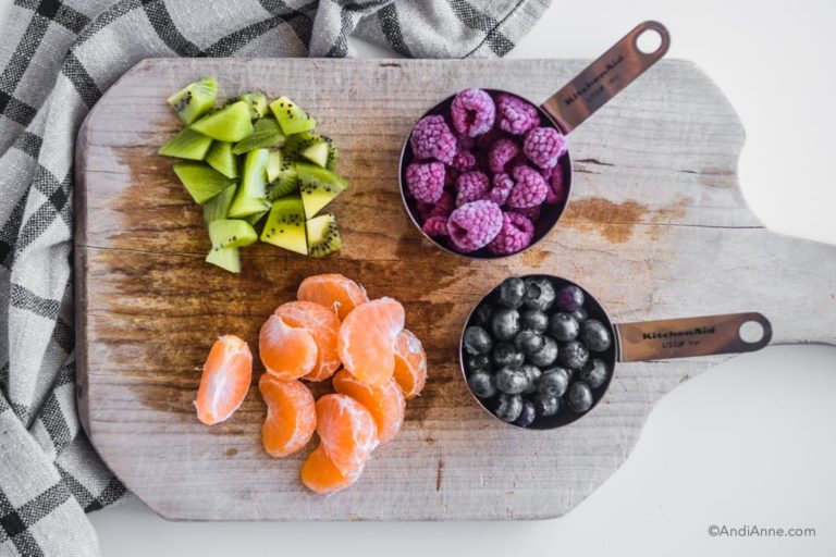 kiwi, raspberries, mandarin orange slices and blueberries on a cutting board