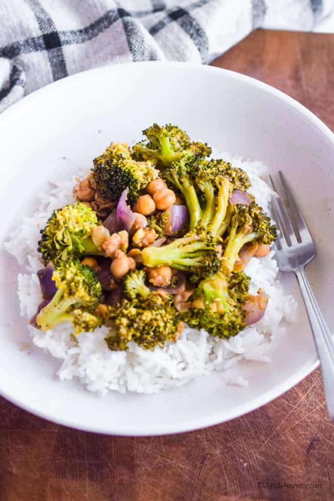 White bowl with jasmine rice and stir fry on top. Fork is on the side of food.