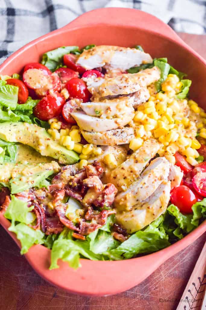 close up detail of maple dijon chicken avocado salad with dressing drizzled overtop.