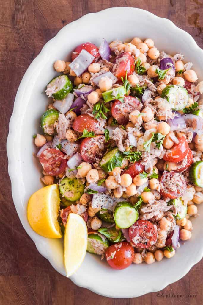 chickpea lemon tuna salad in white bowl with lemon wedges