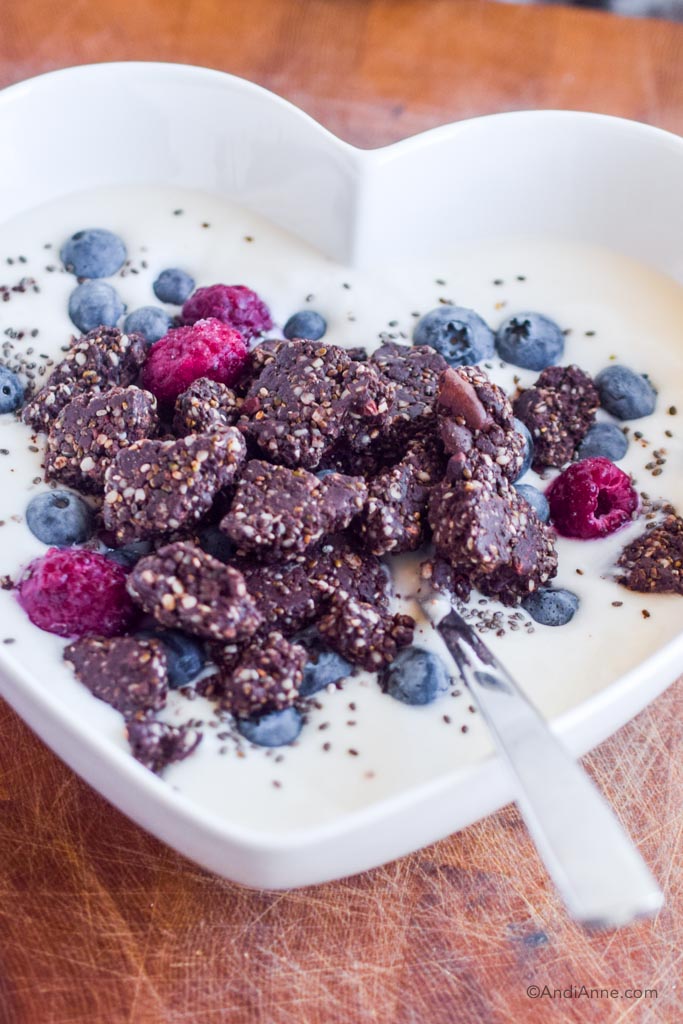 chocolate protein chia bites in a heart bowl with yogurt and fresh berries.