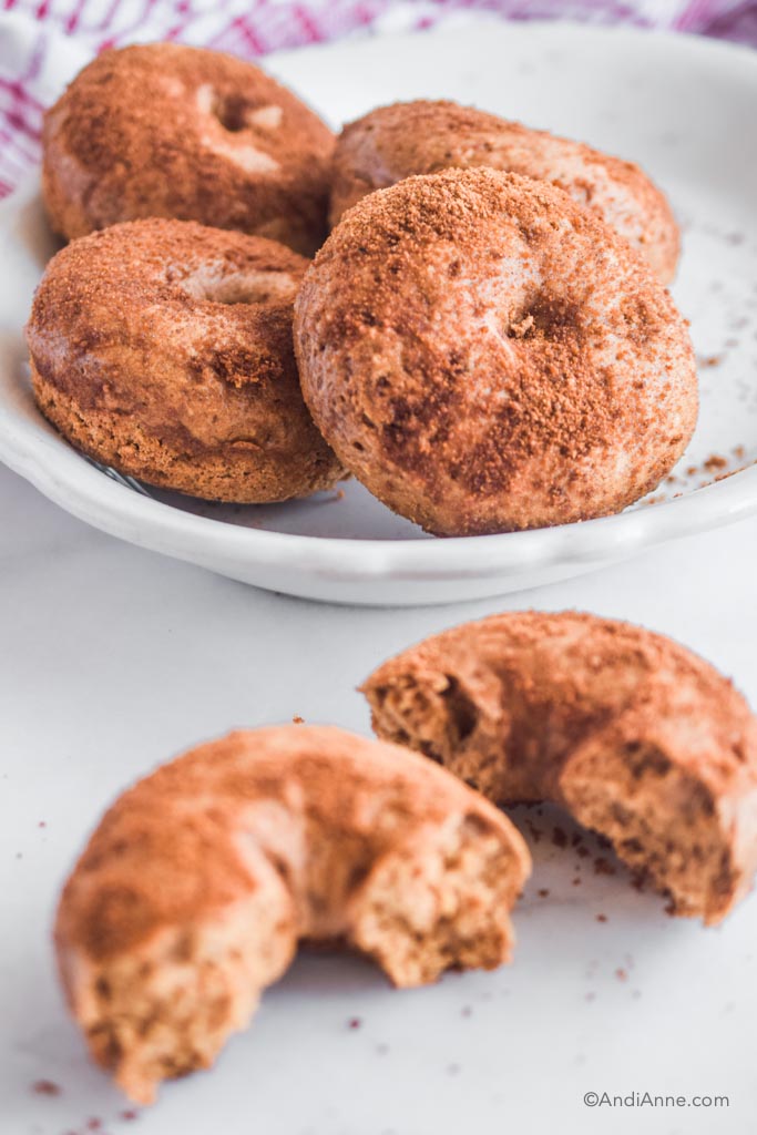 pile of cinnamon sugar baked donuts in a white dish. Once broken apart in the front.