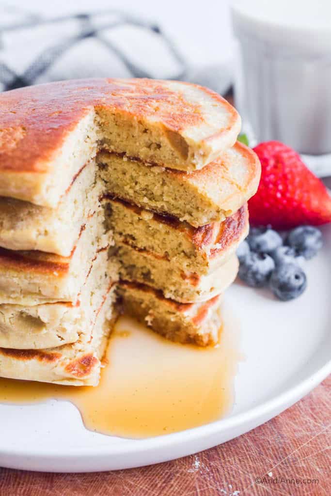 Stack of pancakes cut through. Berries in background.
