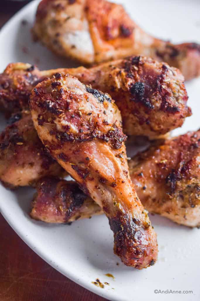 oven baked chicken legs piled together on a white plate