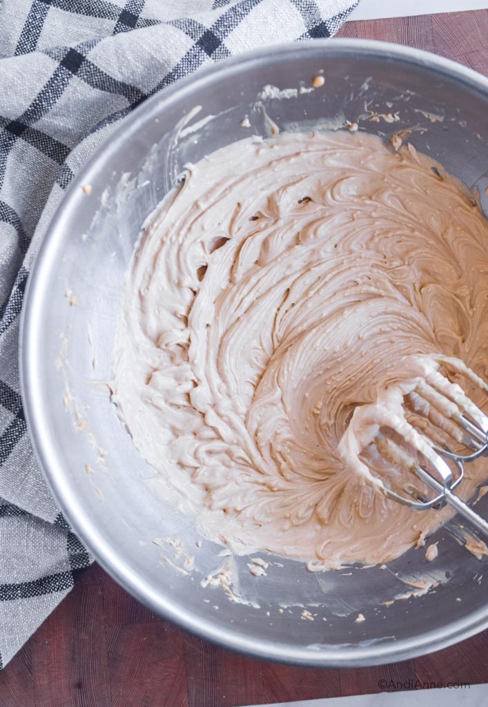 cream cheese frosting without powdered sugar in a large metal bowl with hand mixer on the side