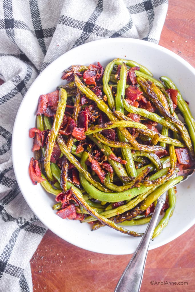 garlic green beans with bacon in a white serving dish with large silver spoon