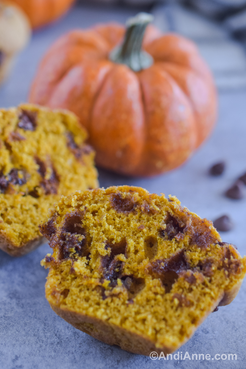 Close up of a muffin sliced in half with a pumpkin in the background.