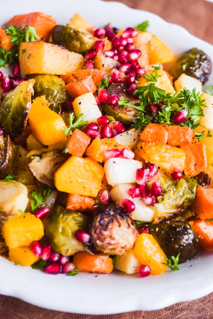roasted root vegetables in a bowl with pomegranate seeds and chopped parsley