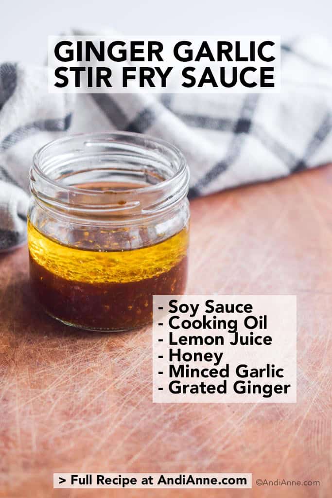 glass jar with ginger garlic stir fry sauce on wood cutting board with kitchen towel behind it
