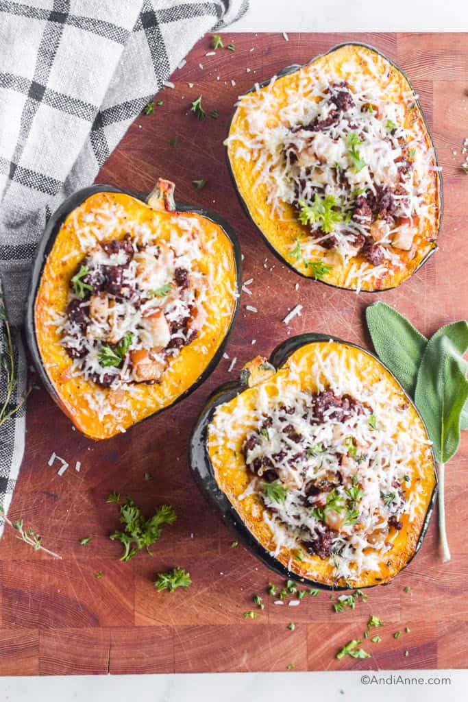 three stuffed acorn squash on a wood cutting board