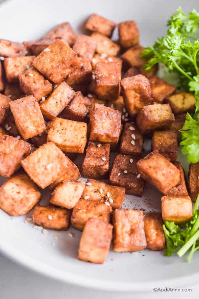 air fryer tofu on a plate with parsley and sesame seeds