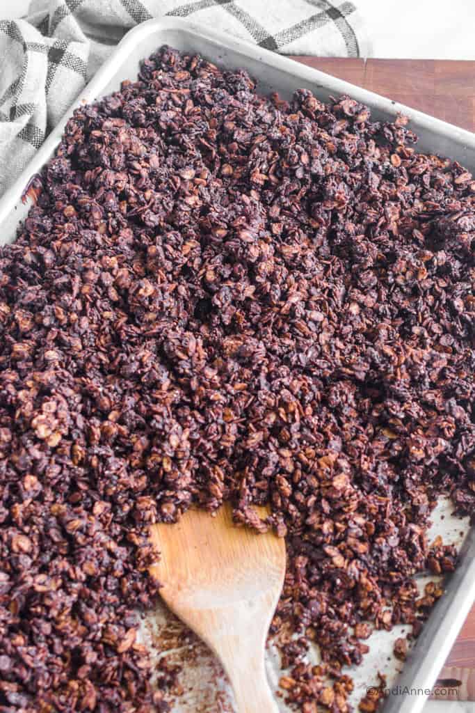 Side angle of the chocolate granola clusters on a baking sheet with wooden spoon