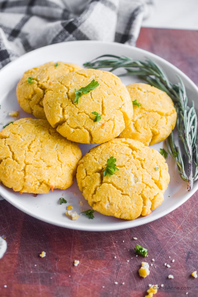 coconut flour biscuits on a white plate with fresh rosemary beside it.