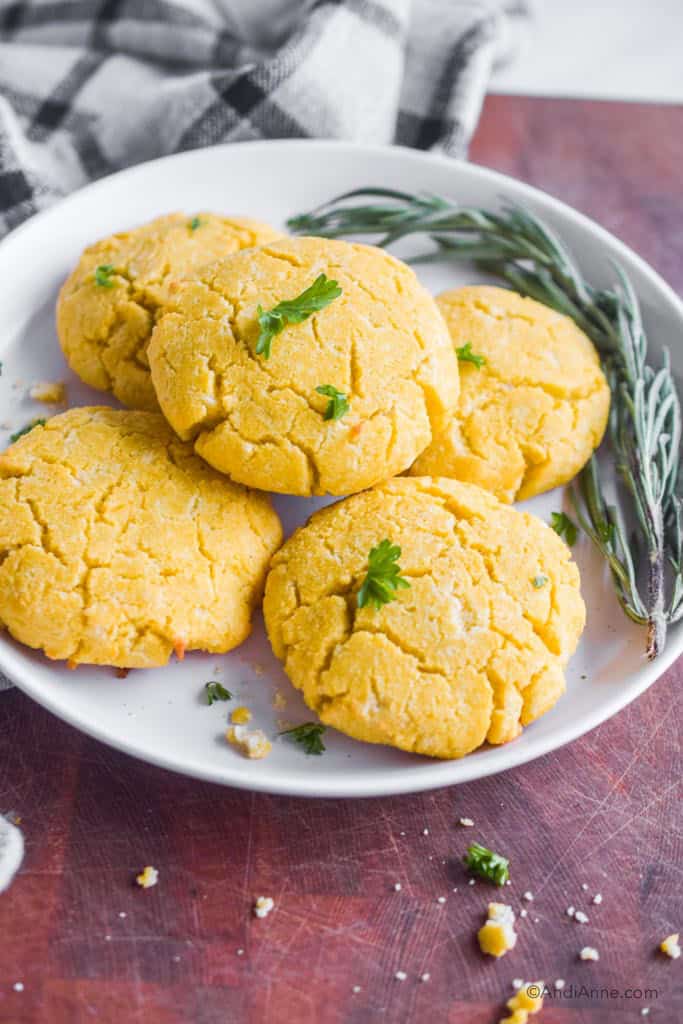 coconut flour biscuits on a white plate with fresh rosemary beside it.