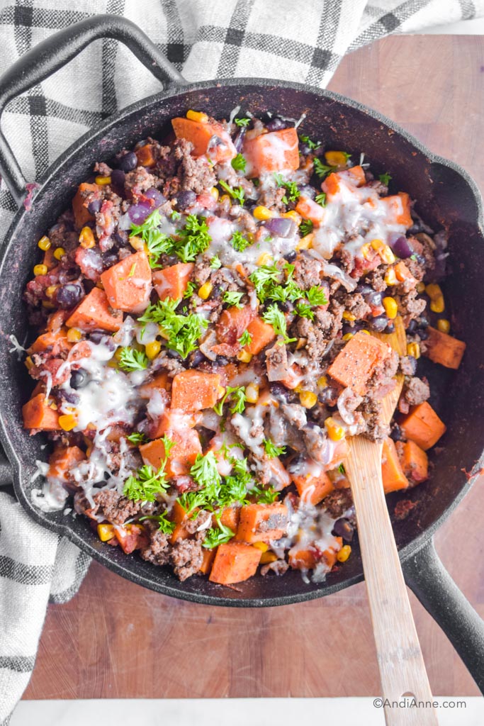 Looking down at a skillet with ground beef, chopped sweet potato, black beans, corn and melted mozzarella cheese. 
