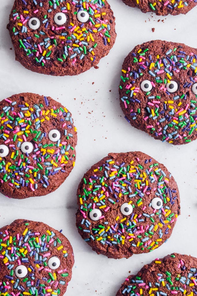 chocolate oat monster cookies with three candy eyeballs and rainbow sprinkles