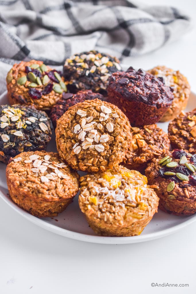 a pile of oatmeal muffins on a white plate. All different colors and flavors.
