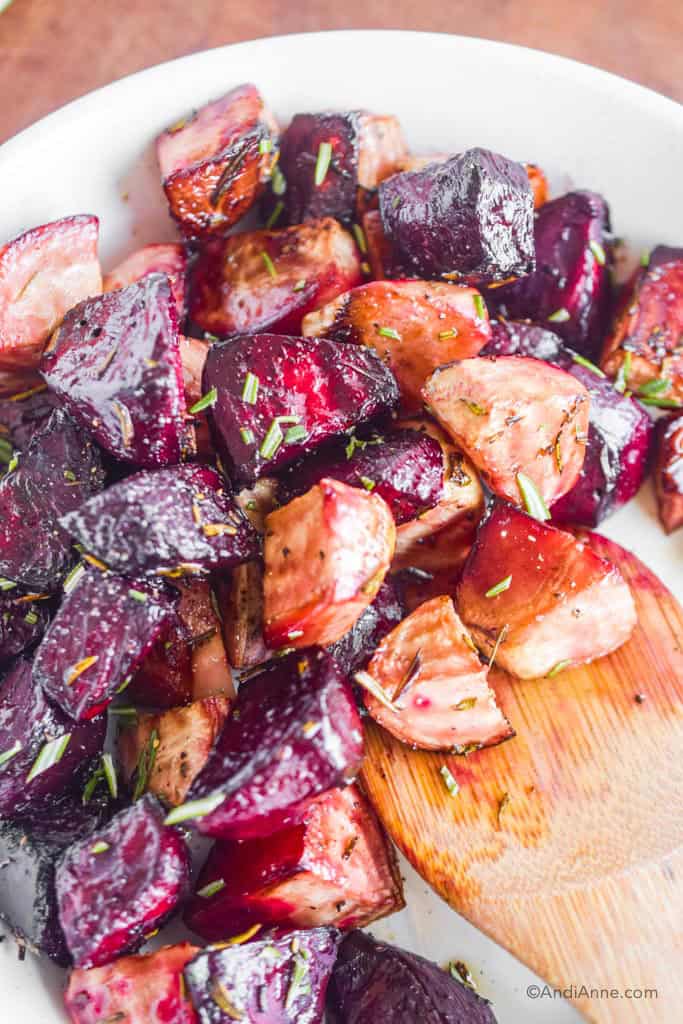 Close detail of cooked red beets and striped beets with a large wooden spoon.