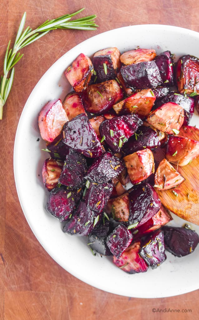 roasted red beets and striped beets in a white bowl with chopped rosemary sprinkled on top.