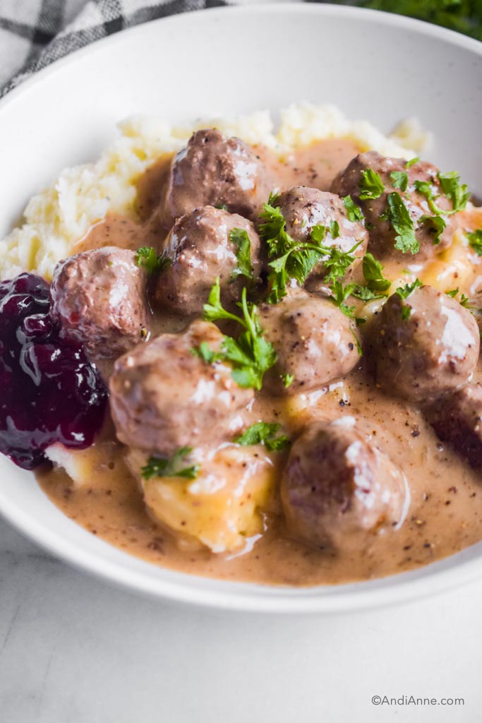 Close up of meatballs, mashed potatoes and lingonberry jam in white dish.