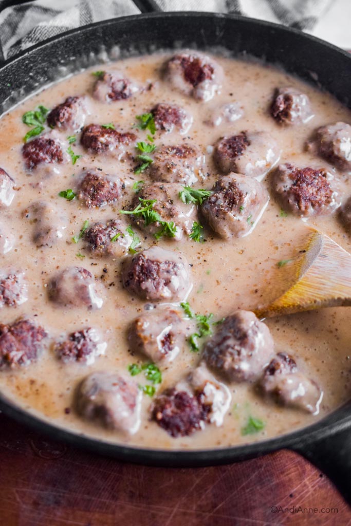 Close up of meatballs in black skillet with gravy sauce.
