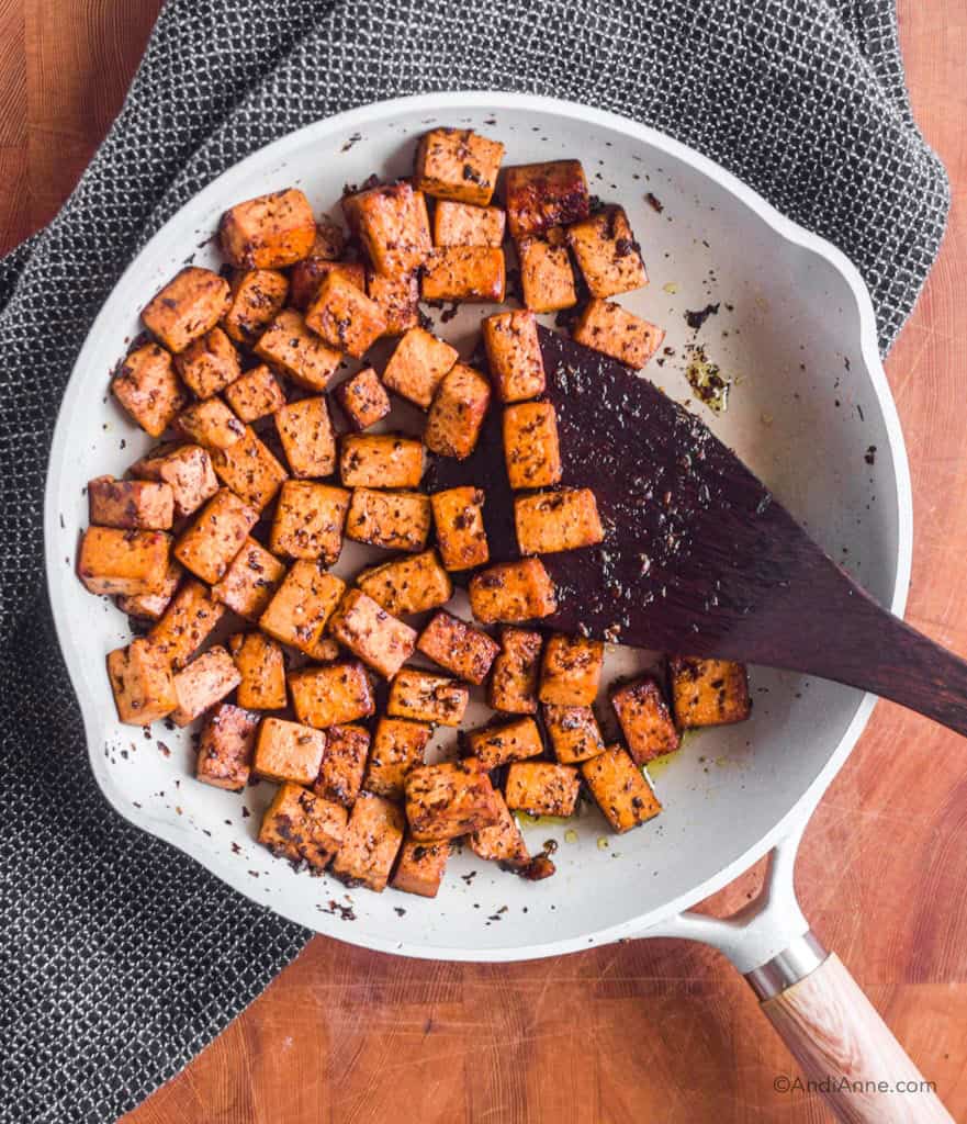 Cooked basil balsamic marinated tofu in a frying pan with a wood spatula
