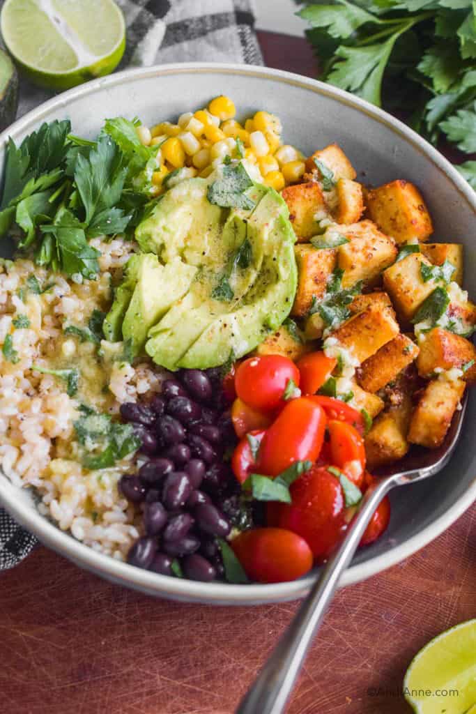 crispy tofu burrito bowl with rice, black beans, cherry tomatoes, avocado, corn and tofu.