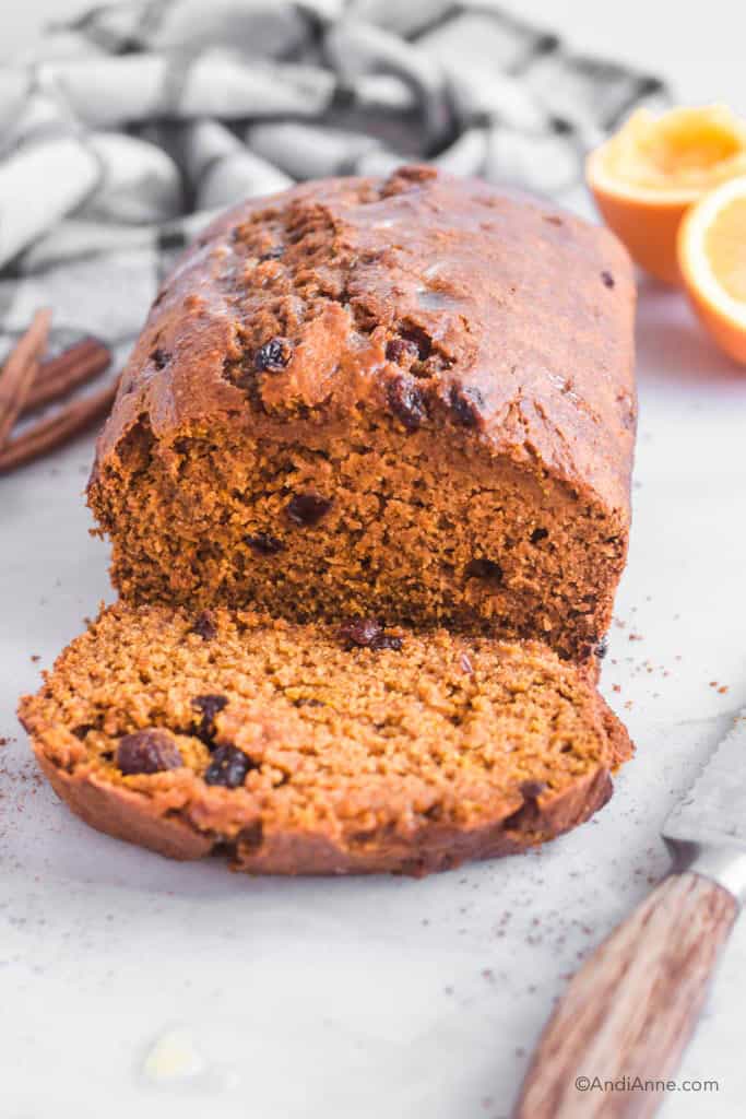 pumpkin raisin bread sliced into with orange and cinnamon behind it
