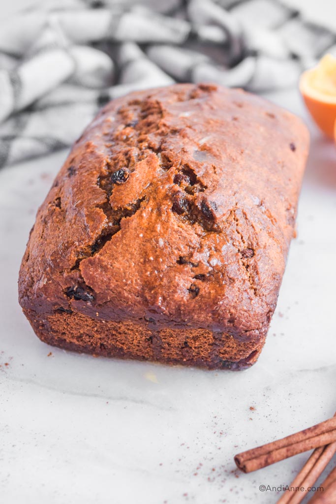 side angle of pumpkin bread with orange and kitchen towel in background