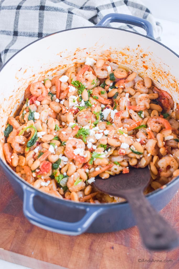 shrimp one-pot dinner with white beans, chopped parsley and feta cheese in a blue pot. 