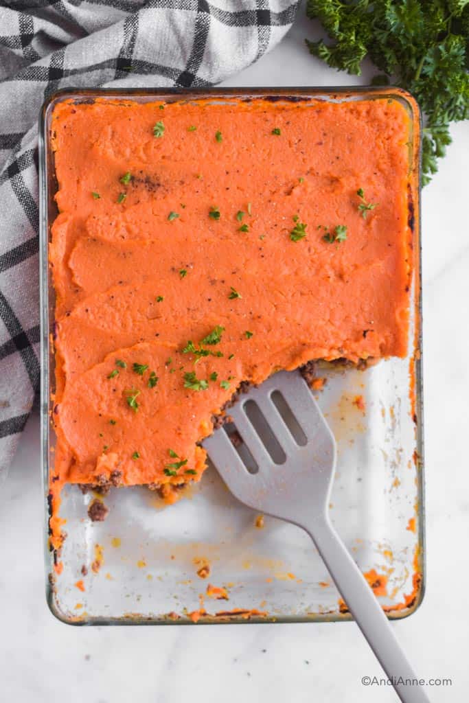 Looking down at the sweet potato shepherds pie with portions taken out of the casserole dish and a spatula inside.