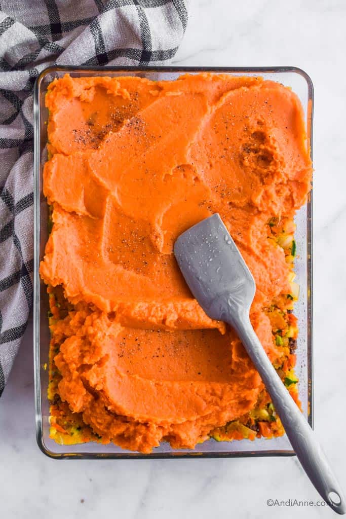 sweet potato shepherds pie in a glass casserole dish with a spatula.