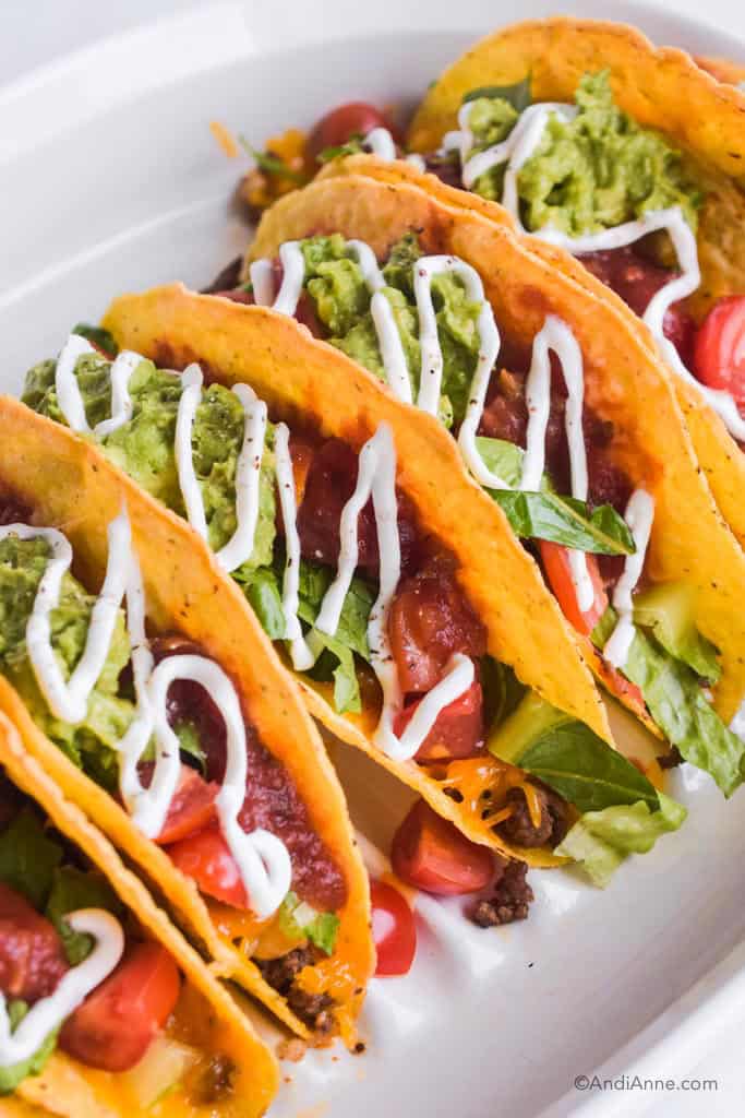 Close up of Beef Rice Chickpea Tacos with guacamole, lettuce and sour cream drizzled on top.