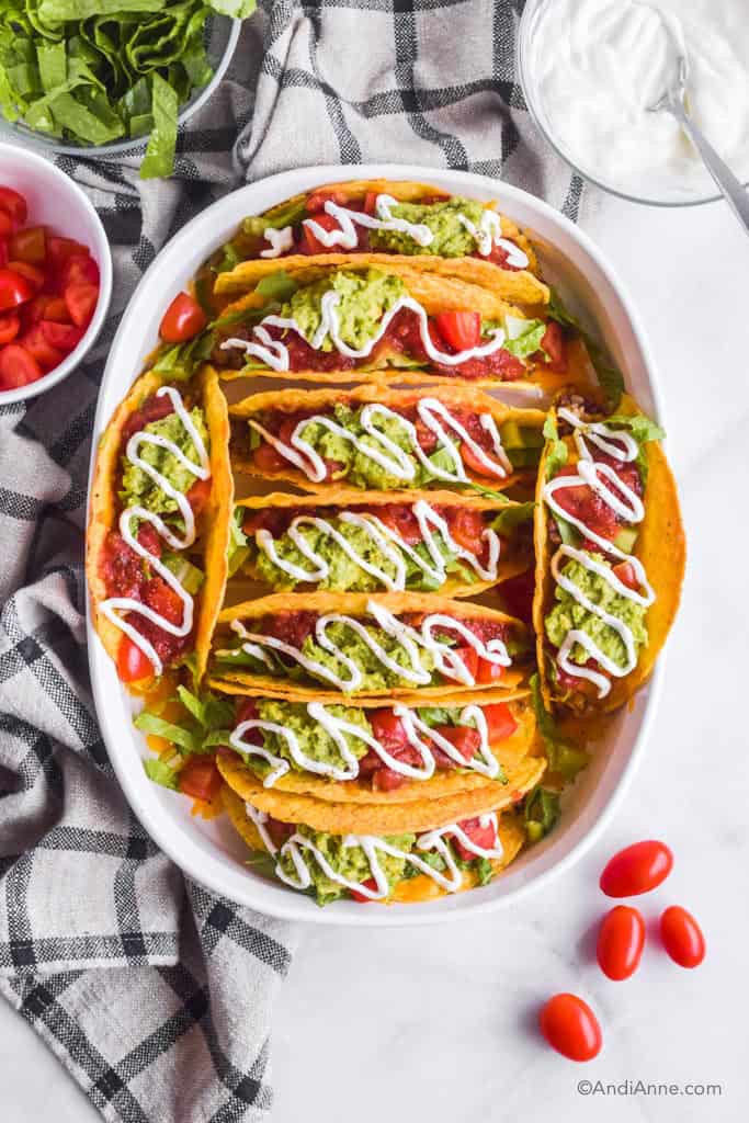 Beef Rice Chickpea Taco Bake in white casserole dish with bowls of sour cream, sliced tomatoes and shredded lettuce surrounding it.