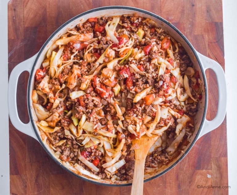 cooked hamburger cabbage casserole in white cast iron pan with wood spoon