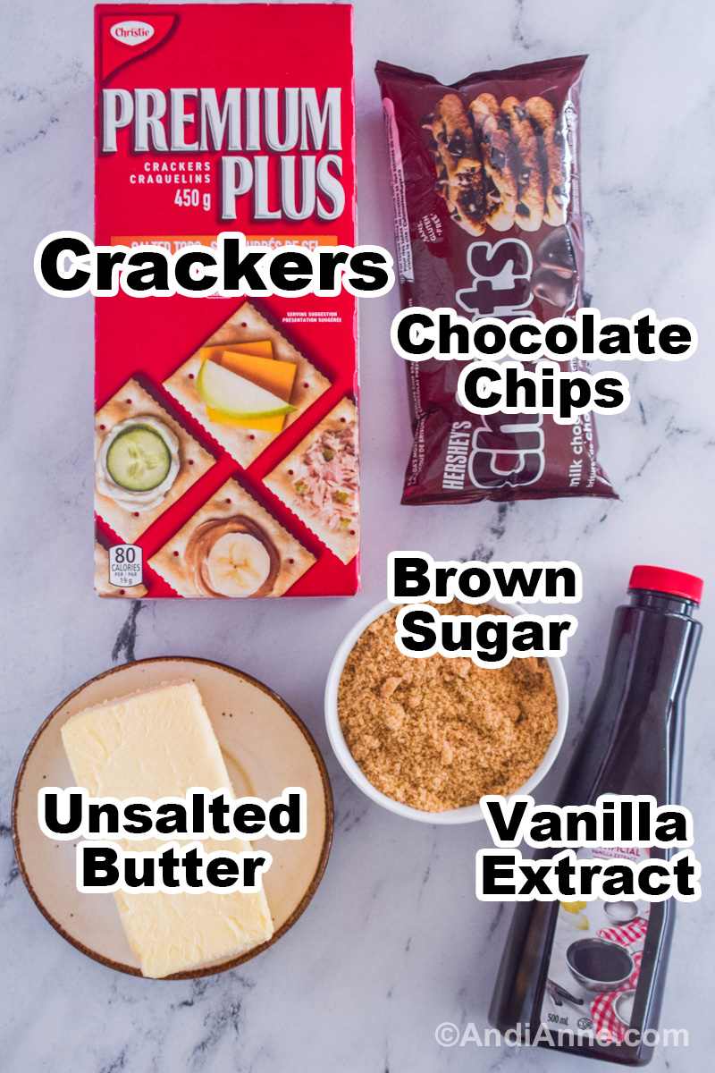 Recipe ingredients on the counter including a box of saltine crackers, chocolate chips, block of butter, bowl with brown sugar, and container of vanilla extract.