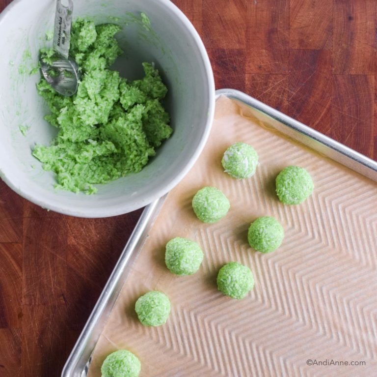 white bowl with 1 Tbsp and green batter. Baking sheet with rolled green jello balls beside it.