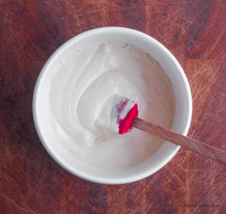 thick cream mixed in white bowl with red spatula