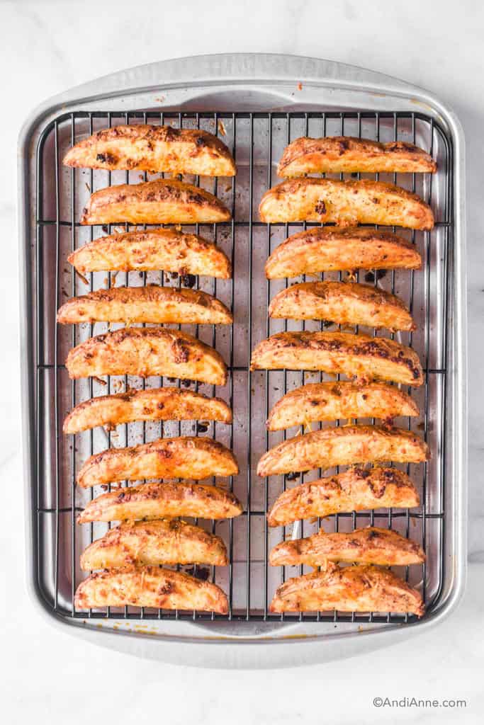 Crispy parmesan potato wedges sitting on a baking rack in a single layer.