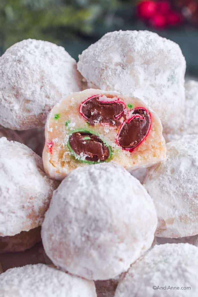 close up of snowball cookies, one sliced in half showing M&Ms and sprinkles hidden inside.