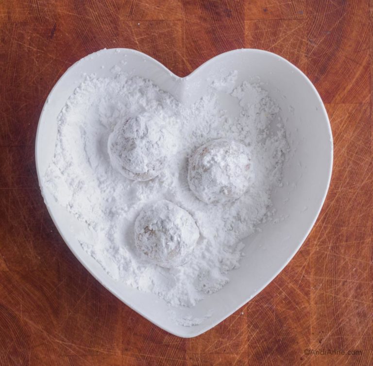 three cookies in heart shaped bowl tossed in confectioners sugar