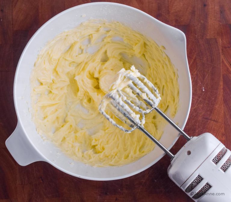 creamed butter and confectioners sugar in white bowl with hand mixer