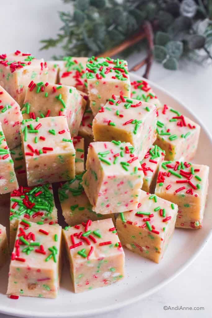 sugar cookie fudge squares with green and red jimmies stacked on a white plate.