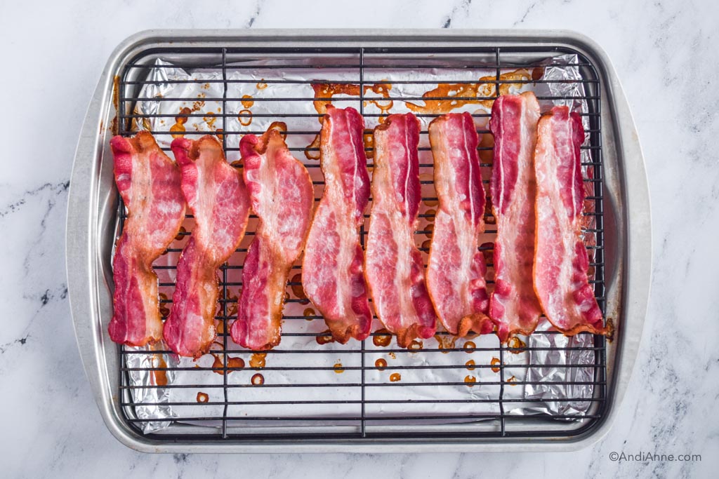 A baking sheet with black rack and cooked bacon strips on top.