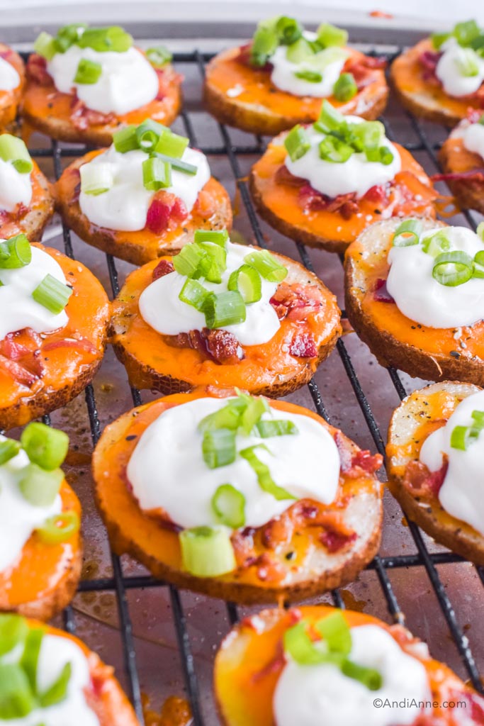 bacon cheese potato slices with sour cream and green onions on baking rack.
